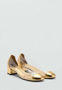 Ballerines dorées avec un dessus translucide, bout en cuir doré brillant et un petit talon block. Texture lisse avec un design moderne.