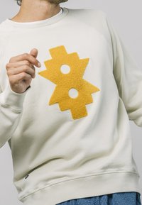 Lichtbeige sweatshirt met een gestructureerd gele grafisch ontwerp met twee uitgesneden cirkels. Comfortabele stof met ribbelboorden en zoom.