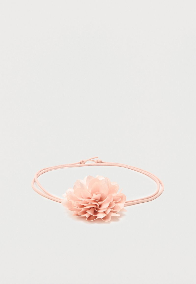 Ροζ ελαστική κορδέλα μαλλιών με απαλό υφασμάτινο λουλούδι με στρωμένα πέταλα στο κέντρο σε λευκό φόντο.