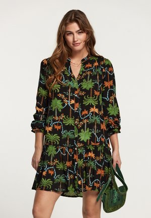 Zwarte jurk met kleurrijke palmen- en bloemenpatronen, knoopsluiting aan de voorkant, lange mouwen en een gelaagde rok, gecombineerd met een groene handtas.