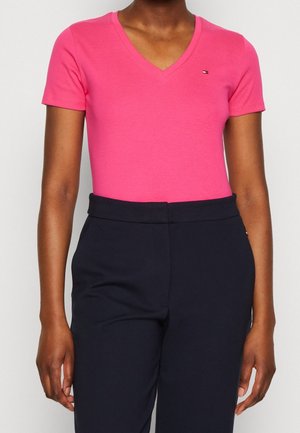 Lyserød T-shirt med V-hals lavet af blød bomuld, korte ærmer, med en tætsiddende silhuet. Kombineret med mørkeblå, højtaljede bukser.