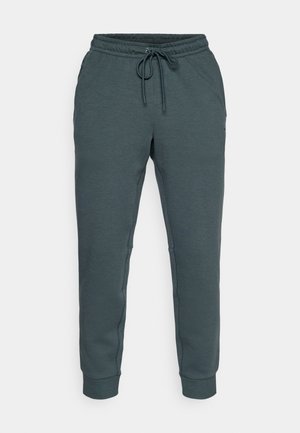 Pantalones de chándal gris oscuro con cinturilla elástica y cordón. Disponen de bolsillos laterales y puños ajustados en los tobillos. Textura suave.