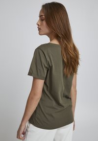 Olivengrøn bomulds t-shirt med korte ærmer, rund hals og en afslappet pasform. Stoffet har en glat tekstur uden synlige mønstre.