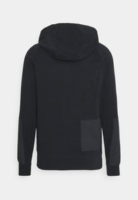 Svart huvtröja med texturerad yta, har en huva, långa ärmar och en ficka på vänster sida. Enkelt design och tät passform.