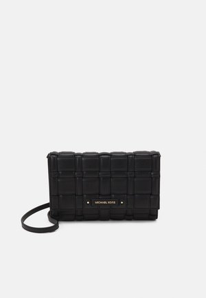 Pochette en cuir tressé noir avec une fine lanière et une plaque logo Michael Kors dorée sur le devant, sur fond blanc.