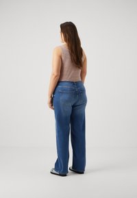 Top sem mangas às riscas em laranja e azul, combinado com uns jeans de ganga azul de cintura alta. Os jeans têm pernas largas com um corte descontraído e bolsos traseiros.