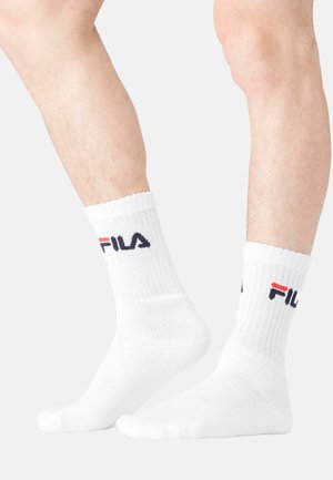 Chaussettes en coton blanc, style crew, avec une texture côtelée, arborant un logo en bleu marine et rouge sur le revers. Design simple et fonctionnel, adapté pour un usage décontracté.