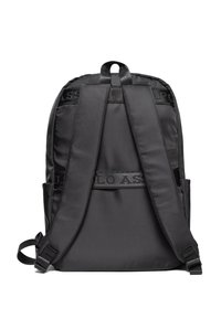 Černý nylonový batoh s polstrovanými ramenními popruhy, středovým pruhem s logem a bočními kapsami. Má hladký povrch a štíhlý tvar.