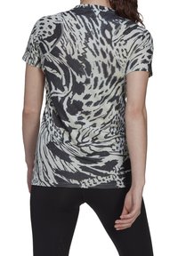 Kvinde iført en kortærmet, sort og hvid abstrakt mønstrede sports T-shirt, vist fra ryggen, parret med sorte leggings.