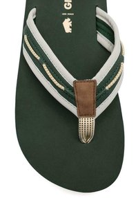 Chancla verde con suela texturizada en verde oscuro, tira gris con detalles de costura y un tirante de dedo en ante sintético marrón.