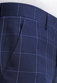 Navy plaid trousers featuring a smooth fabric texture, contrasting light blue grid lines, standard pockets, and a classic waistband design.