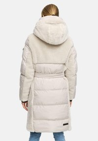 Lichtbeige gewatteerde jas met een zachte fleece capuchon en kraag. Beschikt over een ceintuur in de taille, en gladde en gestructureerde stofsecties.