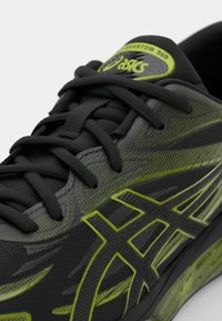 Črne športne čevlje z neon zelenimi poudarki, teksturirano zgornji del in ravne vezalke. Imajo izstopajoč logotip na jeziku in eleganten oblikovni slog.