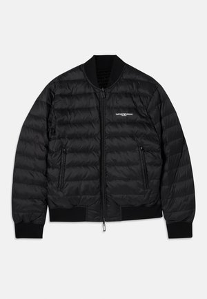 Black puffer jacket with a quilted design, ribbed cuffs and hem, two zippered pockets, and a front zipper closure. Features branding on the chest.