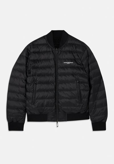 Black puffer jacket with a quilted design, ribbed cuffs and hem, two zippered pockets, and a front zipper closure. Features branding on the chest.