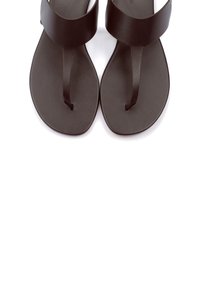 Sandali piatti marroni con una larga cinghia superiore e un post per le dita. Materiale liscio e design minimalista con una suola arrotondata.