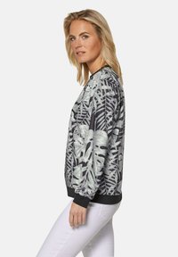 Zwart en grijze bomberjack met een bladerenprint, voorzien van geribde manchetten en zoom, en gemaakt van een soepele, lichte stof.