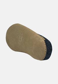 Sottopiede con una base in suede beige tonda e una parte superiore in feltro scuro. Presenta una cucitura lungo il bordo e un marchio impresso.