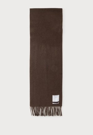 Écharpe en laine marron avec des extrémités à franges et une petite étiquette blanche rectangulaire près d’un bord sur un fond clair uni.