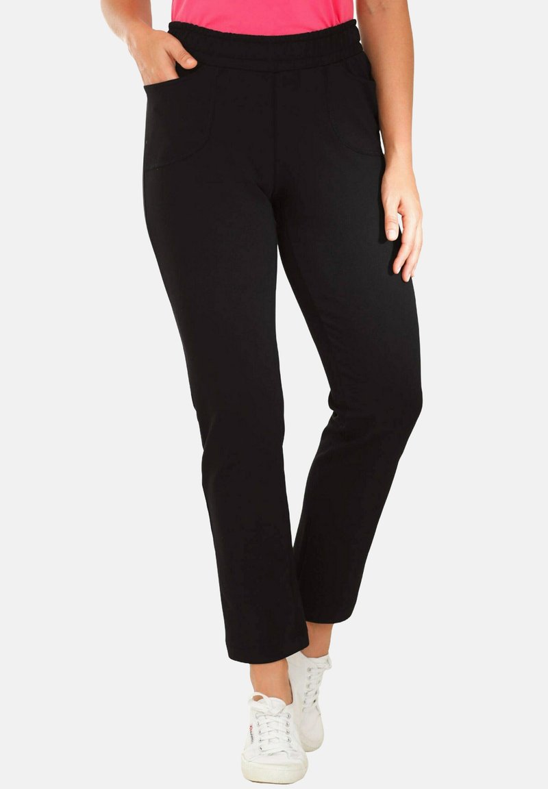 Schwarze Hose mit elastischem Bund und zwei Vorderaschen. Gerades Bein-Design mit glatter Textur, kombiniert mit weißen Sneakers.