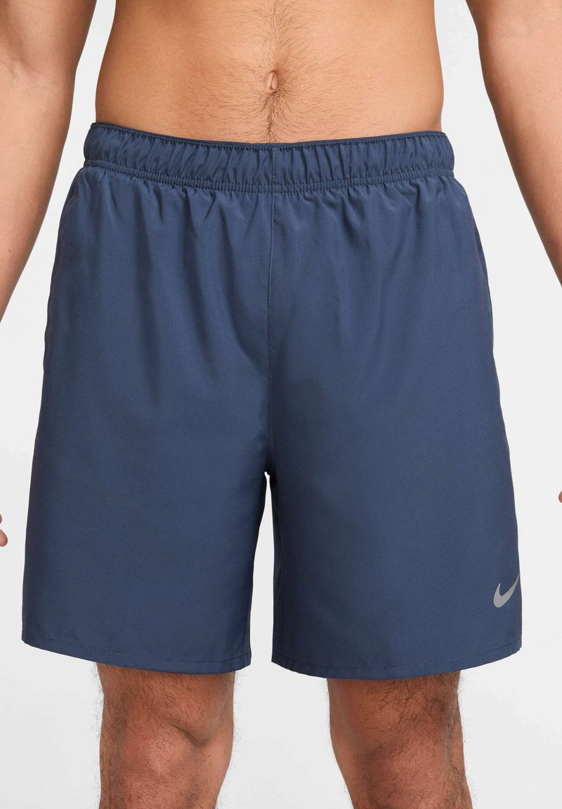 Jūras zila sporta šorti, izgatavoti no viegla auduma, ar elastīgu jostu un mazu sudraba Nike logo apakšējā labajā stūrī.