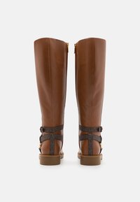 Hoge bruine leren laarzen met een aansluitend ontwerp, decoratieve riemen met een patron accent en gouden hardware aan de achterkant.