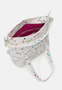 Biała torba z kolorowym wzorem rozprysków, teksturowaną powierzchnią, zamknięciem na zamek i różowym wnętrzem. Wyposażona w regulowany pasek i srebrne elementy metalowe.