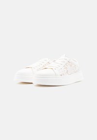 Λευκά αθλητικά παπούτσια με λείο δερμάτινο κάλυμμα στα δάχτυλα, σχέδιο με κορδόνια και ημιδιαφανείς πλευρές από δαντέλα σε υφή λευκής σόλας.