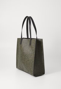 Svart totebag med et teksturert grønt bladmønster, med to svarte stropper og en strukturert form. Laget av slitesterkt materiale.