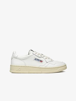 Witte lage sneaker met beige zool, geperforeerde neus, witte veters en "AUTRY"-logo met Amerikaanse vlag op het zijpaneel.