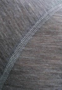 Gray textile featuring a soft, textured surface with a subtle woven pattern. White stitching along the seam adds detail and contrast.