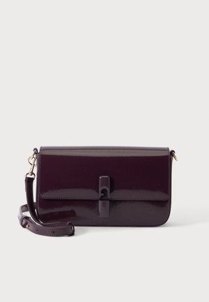 Donkerpaarse glanzende leren crossbodytas met een voorklep en verstelbare riem, liggend op een wit oppervlak.