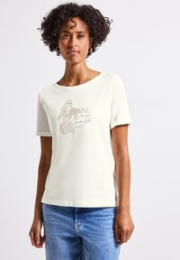 T-shirt couleur crème avec un motif graphique représentant une silhouette et du texte. Manches courtes, col rond et tissu en coton doux.