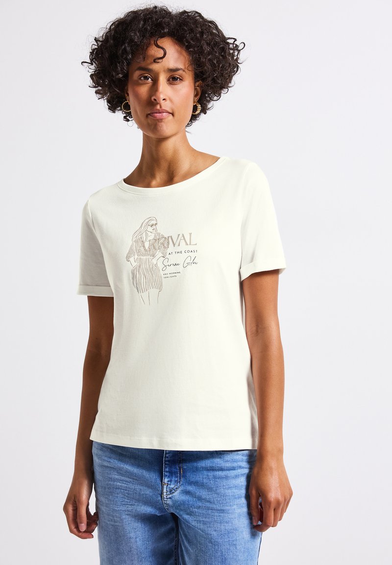 T-shirt couleur crème avec un motif graphique représentant une silhouette et du texte. Manches courtes, col rond et tissu en coton doux.