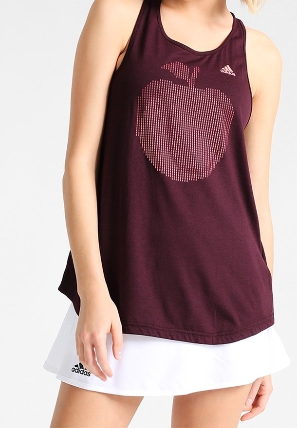 Débardeur bordeaux sans manches avec un motif de pomme en pointillé. Le tissu est léger. Associé à une jupe de sport blanche.