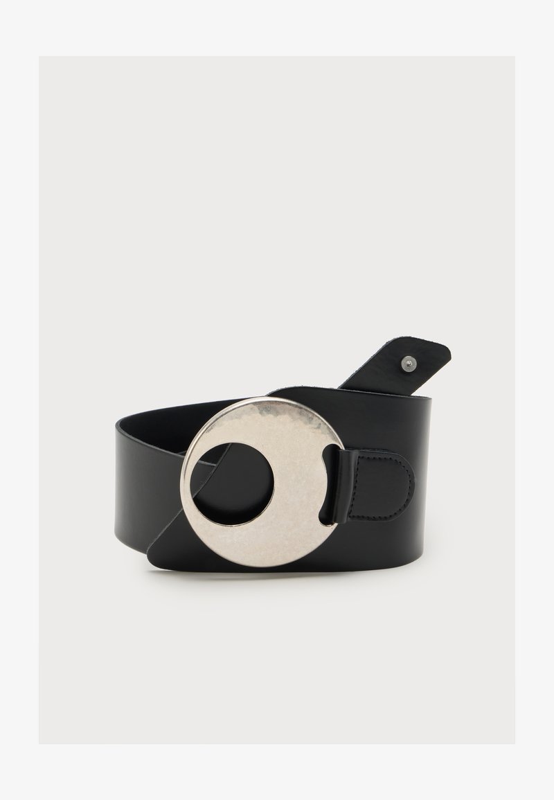 Ceinture en cuir noir avec une grande boucle ronde en argent comportant une découpe circulaire ouverte, présentée enroulée sur fond blanc.