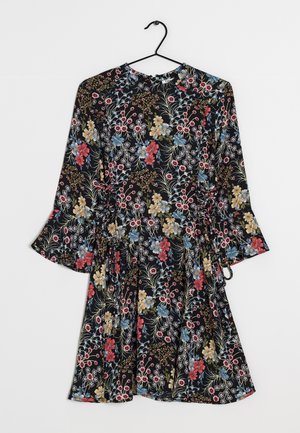 Robe noire fleurie avec des fleurs rouges, bleues et beiges, manches longues cloche et taille cintrée, suspendue sur un cintre noir.