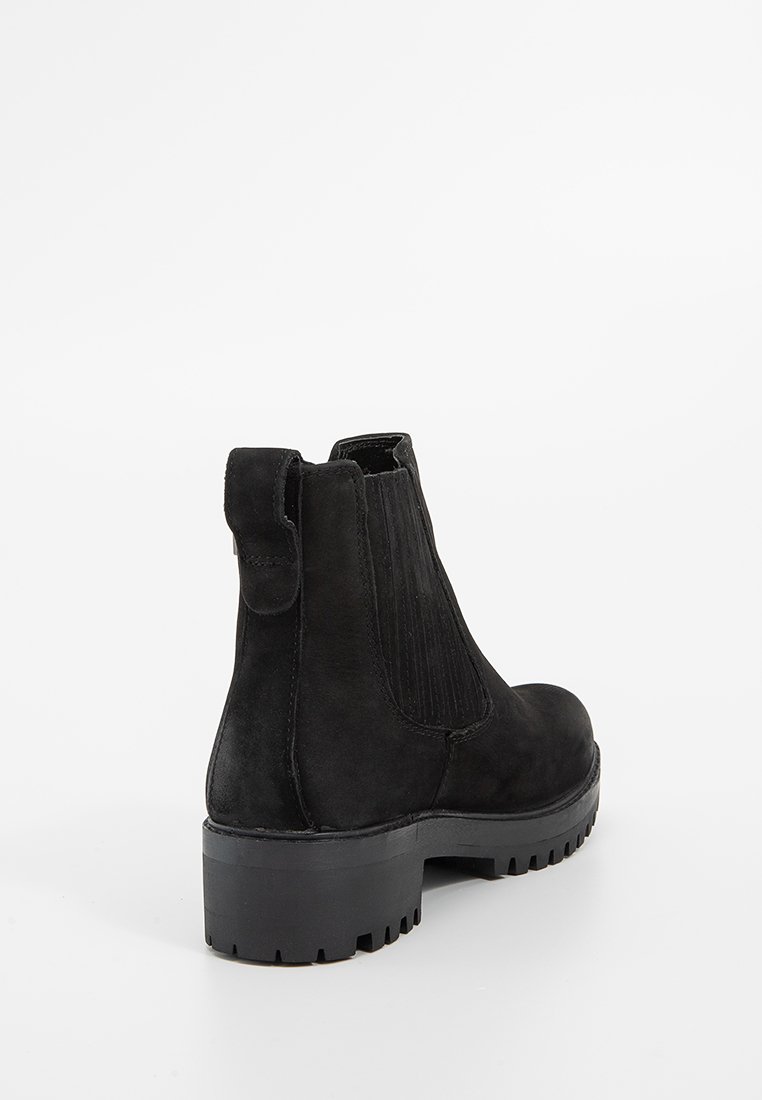 Stivaletti neri in suede con pannelli elastici ai lati, un'etichetta sul tallone e una suola in gomma spessa con un motivo a trama.