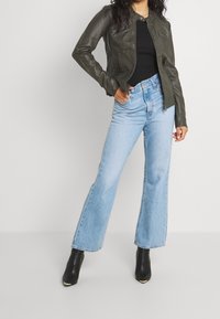 Ciemnozielona skórzana kurtka o dopasowanym kroju, zestawiona z jasnoniebieskimi rozszerzanymi dżinsami. Do stroju dołączone są czarne botki na obcasie.