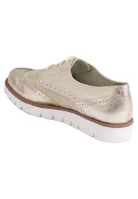 Scarpe oxford in pelle metallica dorata e bianca sporca con dettagli perforati, punta tonda e suola piatta bianca. Texture liscia e tacco basso.