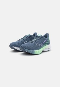 Blauwe en groene sport schoenen met een gestructureerde bovenkant, een verlopen zool en reflecterende accenten. Vetersluiting met een gevoerd kraag en tegenstuk.