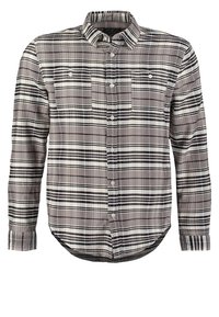 Camicia in flanella a quadri grigia e nera, con chiusura a bottoni, due tasche sul petto, maniche lunghe e orlo curvo.