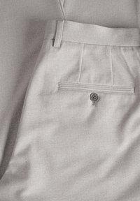 Világosszürke nadrág, texturált anyagból készült, elöl gyűrött, hátul egy gombos zsebével.