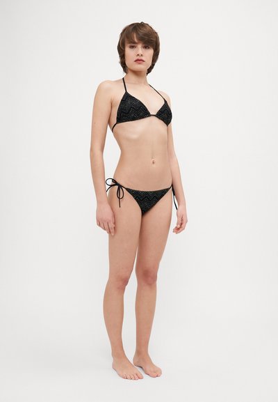 Μαύρο μπικίνι με ζιγκ-ζαγκ σχέδιο, με τρίγωνο τοπ και εσώρουχα με κόμπους στο πλάι. Το υλικό φαίνεται λείο με ελάχιστους μεταλλικούς αξεσουάρ.