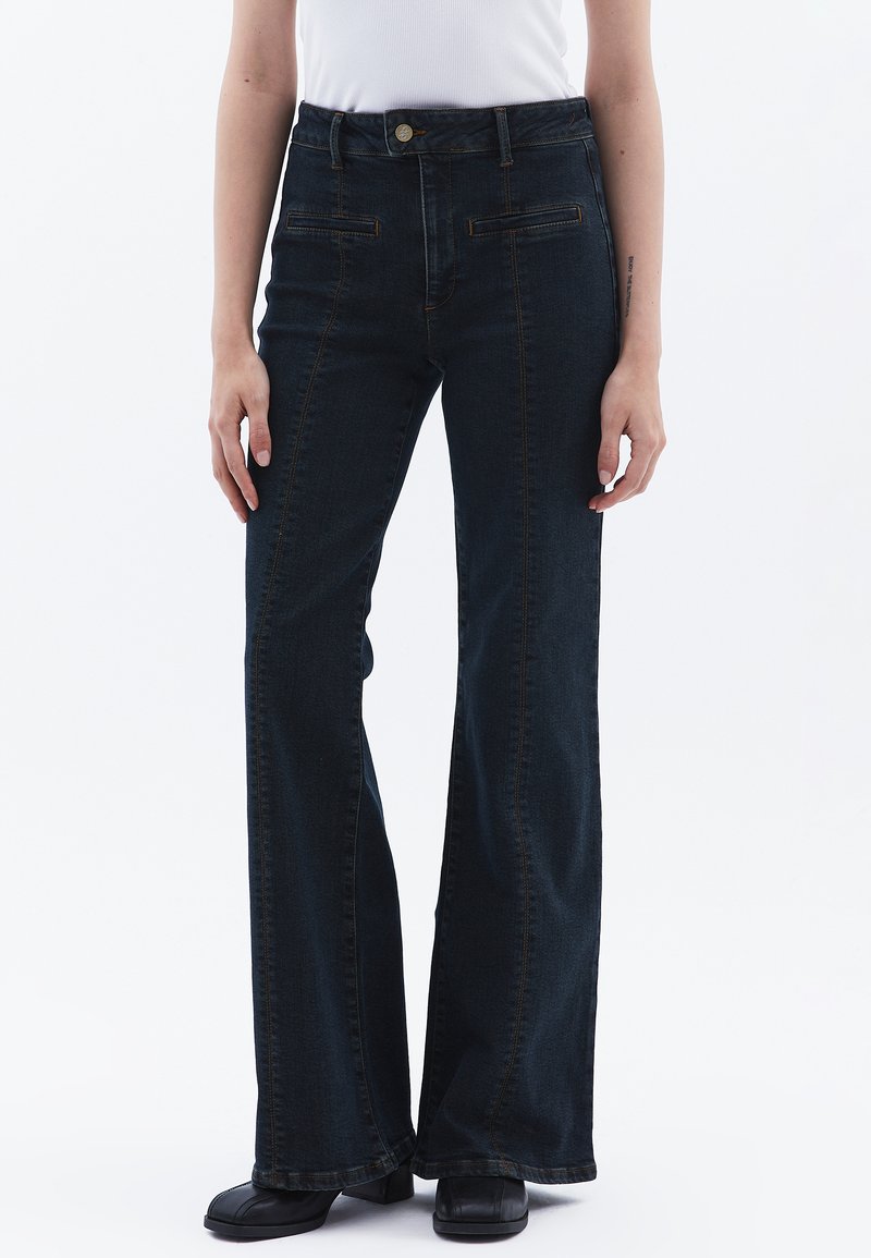 Tmavě modré zvonové džíny vyrobené z denimu, s předními kapsami, jemným prošíváním a vysokým pasem.