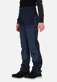 Granatowe spodnie outdoorowe z kieszeniami na zamek, elastycznym paskiem w talii i wzmocnionym szwem. Materiał jest trwały, odpowiedni do aktywnego noszenia.