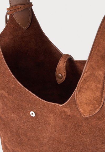 Sac à main en daim marron avec garniture en cuir, une lanière intérieure avec un bouton-pression et une fermeture métallique à l'avant.