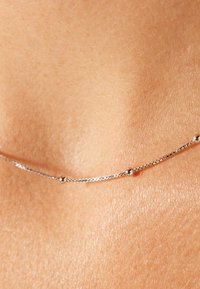 Zilveren ketting met een delicate schakelkettinkje met kleine ronde kralen, nauw op de huid met een gladde textuur. Eenvoudig en minimalistisch ontwerp.