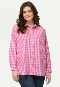 Camicia a quadri rosa e bianca con bottoni, maniche lunghe e colletto, caratterizzata da una vestibilità rilassata e una texture di cotone morbida.