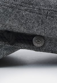Casquette en mélange de laine grise avec une finition texturée. Présente un accent en corde tressée et un bouton métallique rond avec un logo gravé.